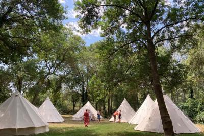 Groupe de personnes réunies en soirée en plein air, avec tables décorées et guirlandes lumineuses suspendues.