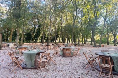 Groupe de personnes réunies en soirée en plein air, avec tables décorées et guirlandes lumineuses suspendues.