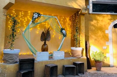 Groupe de personnes réunies en soirée en plein air, avec tables décorées et guirlandes lumineuses suspendues.
