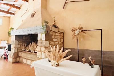 Groupe de personnes réunies en soirée en plein air, avec tables décorées et guirlandes lumineuses suspendues.