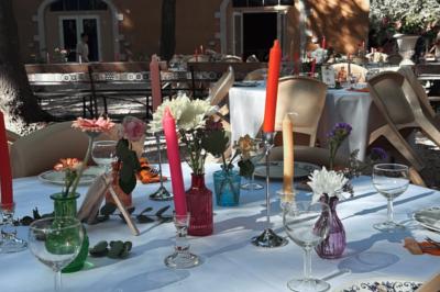 Groupe de personnes réunies en soirée en plein air, avec tables décorées et guirlandes lumineuses suspendues.