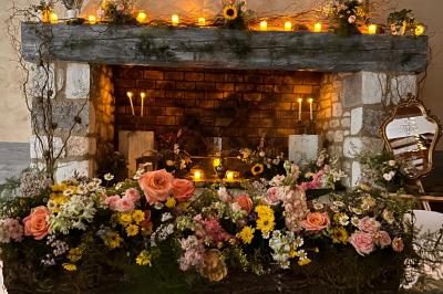 Groupe de personnes réunies en soirée en plein air, avec tables décorées et guirlandes lumineuses suspendues.