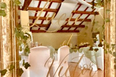 Groupe de personnes réunies en soirée en plein air, avec tables décorées et guirlandes lumineuses suspendues.