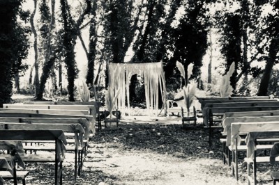 Groupe de personnes réunies en soirée en plein air, avec tables décorées et guirlandes lumineuses suspendues.