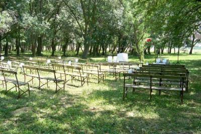 Groupe de personnes réunies en soirée en plein air, avec tables décorées et guirlandes lumineuses suspendues.