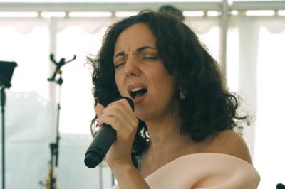 Un groupe de musiciens et une chanteuse se produisent sur scène sous des lumières colorées.