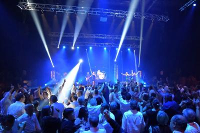 Un groupe de musiciens et une chanteuse se produisent sur scène sous des lumières colorées.