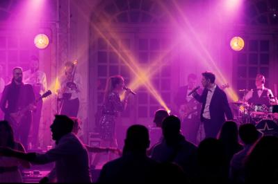 Un groupe de musiciens et une chanteuse se produisent sur scène sous des lumières colorées.