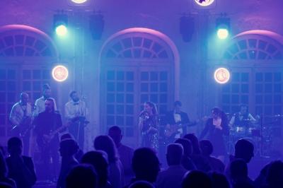 Un groupe de musiciens et une chanteuse se produisent sur scène sous des lumières colorées.