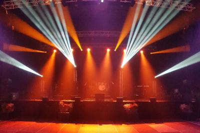 Un groupe de musiciens et une chanteuse se produisent sur scène sous des lumières colorées.