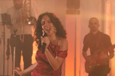 Un groupe de musiciens et une chanteuse se produisent sur scène sous des lumières colorées.