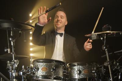 Un groupe de musiciens et une chanteuse se produisent sur scène sous des lumières colorées.