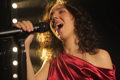 Un groupe de musiciens et une chanteuse se produisent sur scène sous des lumières colorées.