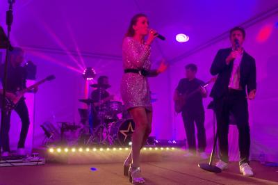 Un groupe de musiciens et une chanteuse se produisent sur scène sous des lumières colorées.