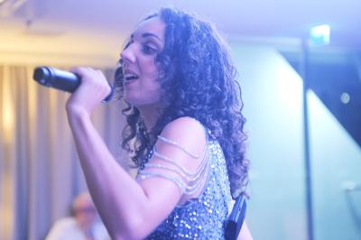 Un groupe de musiciens et une chanteuse se produisent sur scène sous des lumières colorées.