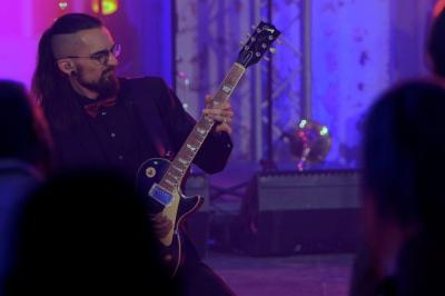 Un groupe de musiciens et une chanteuse se produisent sur scène sous des lumières colorées.