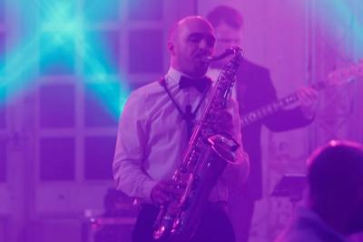 Un groupe de musiciens et une chanteuse se produisent sur scène sous des lumières colorées.