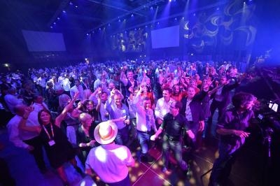 Groupe de personnes dansant et célébrant sous des lumières colorées dans une grande salle.