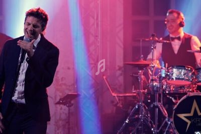 Un groupe de musiciens et une chanteuse se produisent sur scène dans une ambiance lumineuse tamisée.