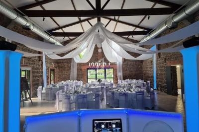 Salle de réception décorée avec des tables rondes dressées, des nappes blanches et des voilages suspendus au plafond.