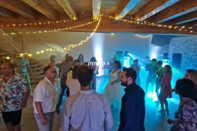 Des personnes dansent dans une salle éclairée par des lumières colorées, avec des guirlandes lumineuses au plafond.