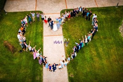 Photo aérienne de personnes formant un grand cœur sur une pelouse, avec un couple au centre.