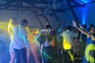 Des personnes dansent sous des jeux de lumière colorés dans une salle avec un plafond en poutres apparentes.