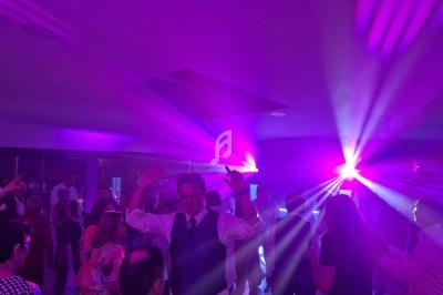 Personnes dansant sous des lumières violettes et roses dans une ambiance festive en intérieur.