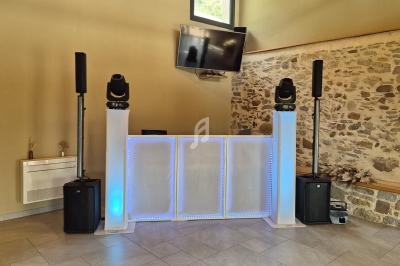 Installation de matériel de sonorisation et d'éclairage avec une table de DJ dans une salle aux murs en pierre.