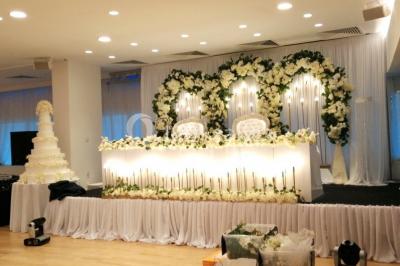 Buffet élégant avec plats variés disposés sur des tables noires, décoré de fleurs blanches dans une salle lumineuse.