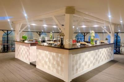 Buffet élégant avec plats variés disposés sur des tables noires, décoré de fleurs blanches dans une salle lumineuse.