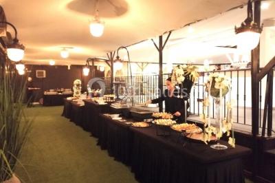 Buffet élégant avec plats variés disposés sur des tables noires, décoré de fleurs blanches dans une salle lumineuse.
