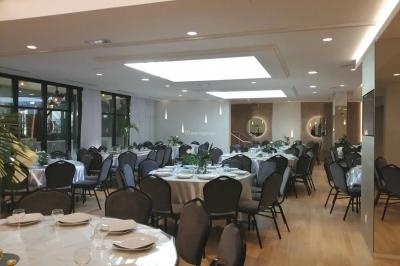Buffet élégant avec plats variés disposés sur des tables noires, décoré de fleurs blanches dans une salle lumineuse.