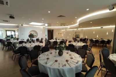 Buffet élégant avec plats variés disposés sur des tables noires, décoré de fleurs blanches dans une salle lumineuse.