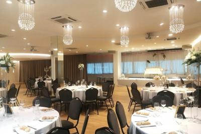 Buffet élégant avec plats variés disposés sur des tables noires, décoré de fleurs blanches dans une salle lumineuse.