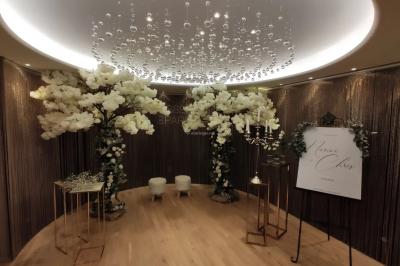 Buffet élégant avec plats variés disposés sur des tables noires, décoré de fleurs blanches dans une salle lumineuse.