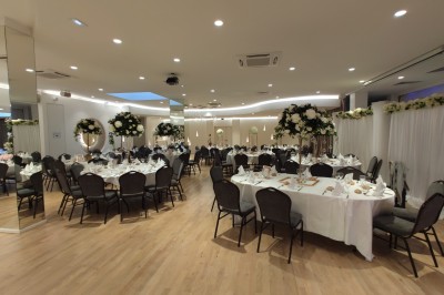Buffet élégant avec plats variés disposés sur des tables noires, décoré de fleurs blanches dans une salle lumineuse.