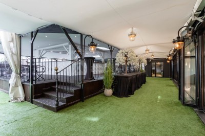 Buffet élégant avec plats variés disposés sur des tables noires, décoré de fleurs blanches dans une salle lumineuse.