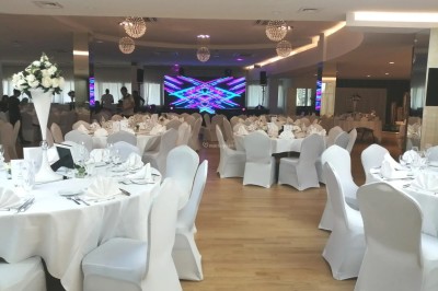 Buffet élégant avec plats variés disposés sur des tables noires, décoré de fleurs blanches dans une salle lumineuse.
