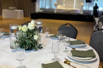 Buffet élégant avec plats variés disposés sur des tables noires, décoré de fleurs blanches dans une salle lumineuse.