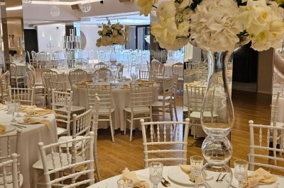 Buffet élégant avec plats variés disposés sur des tables noires, décoré de fleurs blanches dans une salle lumineuse.