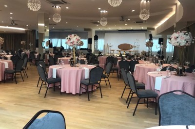 Buffet élégant avec plats variés disposés sur des tables noires, décoré de fleurs blanches dans une salle lumineuse.