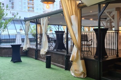 Salle de réception élégante avec tables rondes dressées, chaises transparentes et décorations florales.