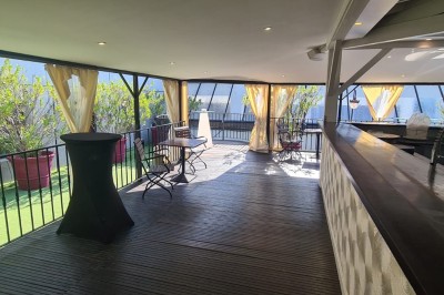 Salle de réception élégante avec tables rondes dressées, chaises transparentes et décorations florales.