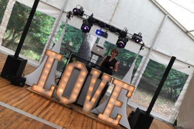 Un groupe de cinq personnes pose sous une tente éclairée, avec des équipements audio visibles en arrière-plan.