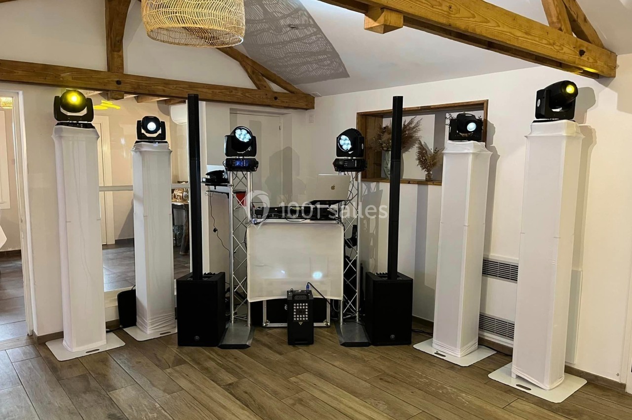 Équipement de sonorisation et éclairage installé dans une salle avec poutres apparentes et parquet en bois.