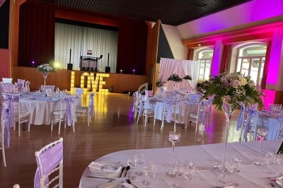 Salle de réception décorée avec des tables élégantes, des fleurs et des lettres lumineuses formant le mot ’LOVE’.