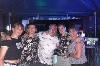 Un groupe de cinq personnes pose sous une tente, entouré d'équipements audio et d'éclairages colorés.