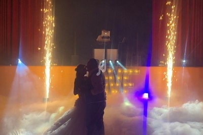 Un couple danse au milieu d'une scène entourée de fumée, d'étincelles et de lumières colorées.