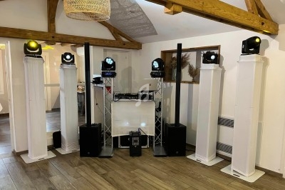 Installation de matériel de sonorisation et d'éclairage dans une salle avec poutres apparentes et parquet en bois.